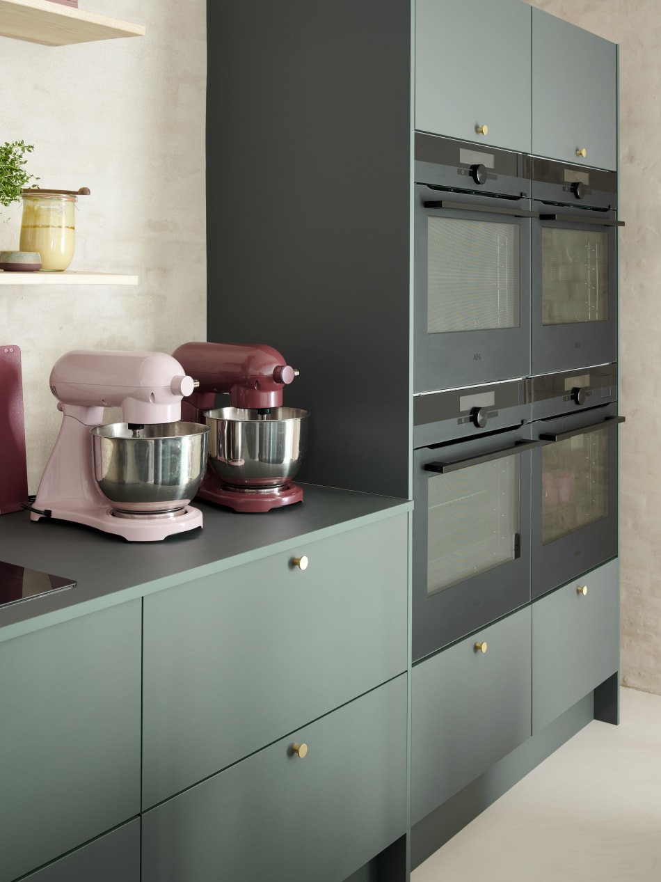 Green kitchen cabinets with pink mixers on countertop | HTH