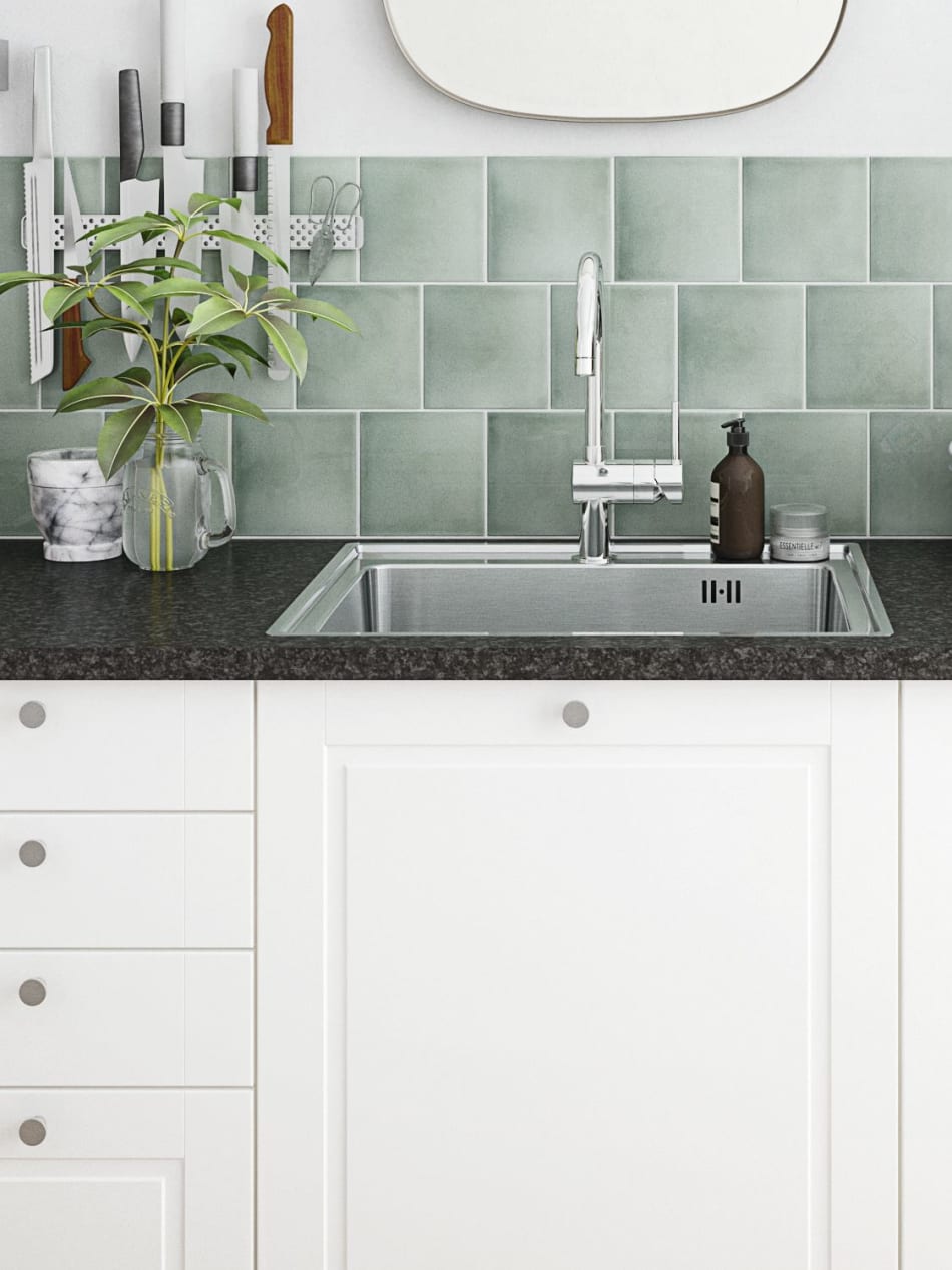 White kitchen cabinets with black countertop and green tile backsplash. Sense Kitchen | HTH