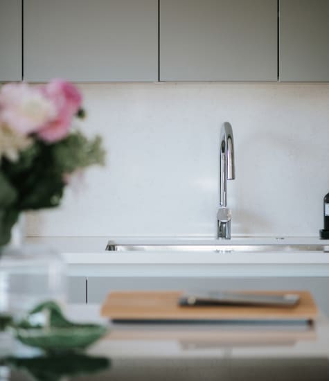 Gray kitchen cabinets with a white countertop and sink | HTH