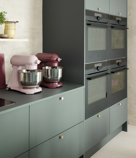 Green kitchen cabinets with built-in ovens and mixers on countertop | HTH
