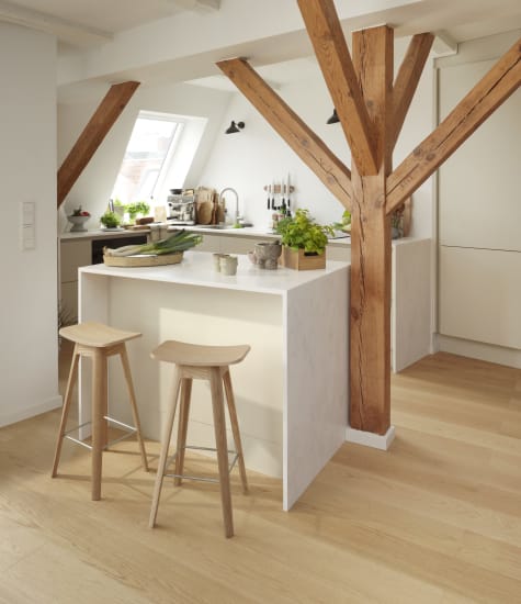 White kitchen with wooden beams and stools, light wood flooring, white cabinets | HTH