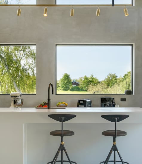 White kitchen island with two stools and a black cabinet in the background | HTH