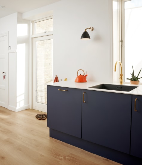 Navy blue kitchen cabinets with light wood floor and white countertop | HTH