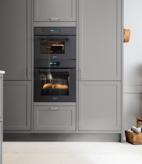 Gray kitchen cabinets with built-in oven and white countertop. Model Art | HTH