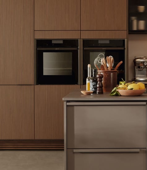 Brown kitchen cabinets with integrated ovens and a gray countertop. Nordic Atmosphere | HTH