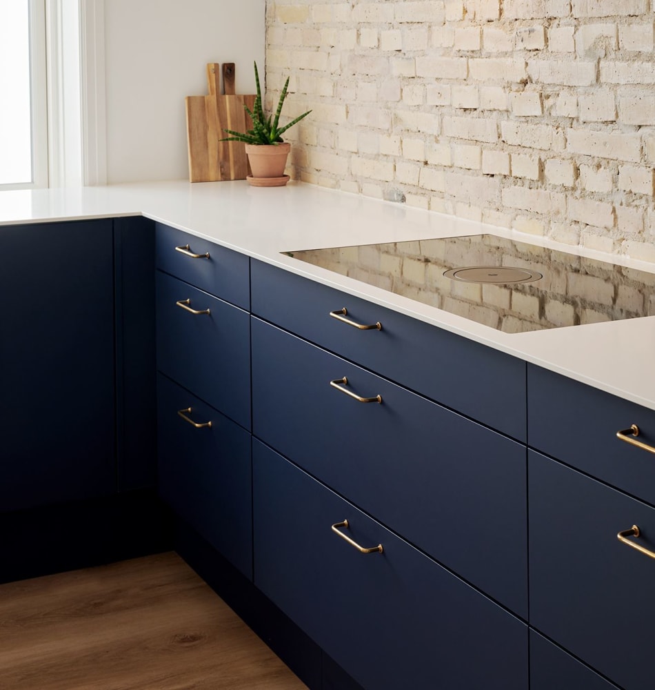 Blue kitchen cabinets with white countertop and brick wall background | HTH