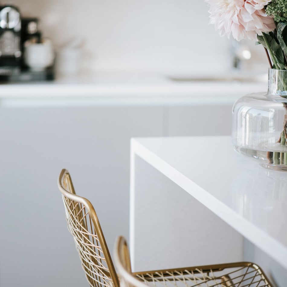 White kitchen island with gold chairs and vase with flowers | HTH