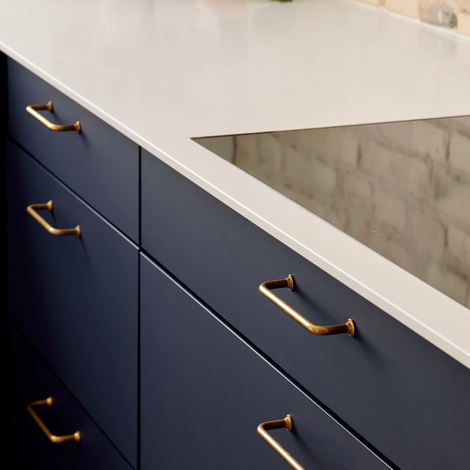 Blue kitchen cabinets with brass handles and white countertop | HTH