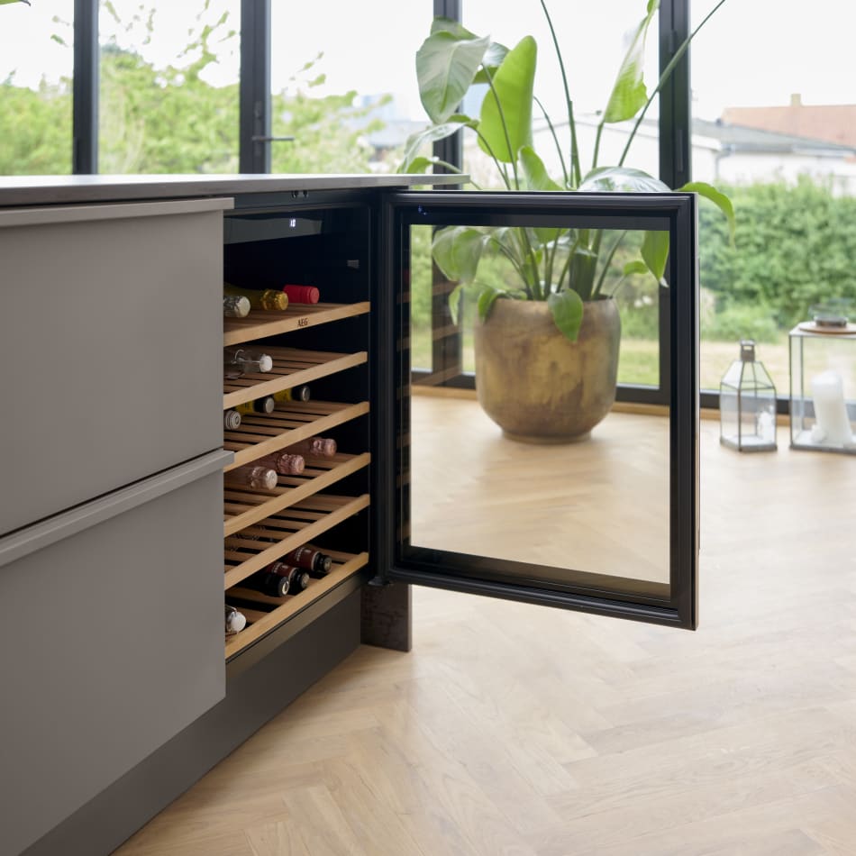Gray kitchen island with open wine cooler and wooden shelves | HTH