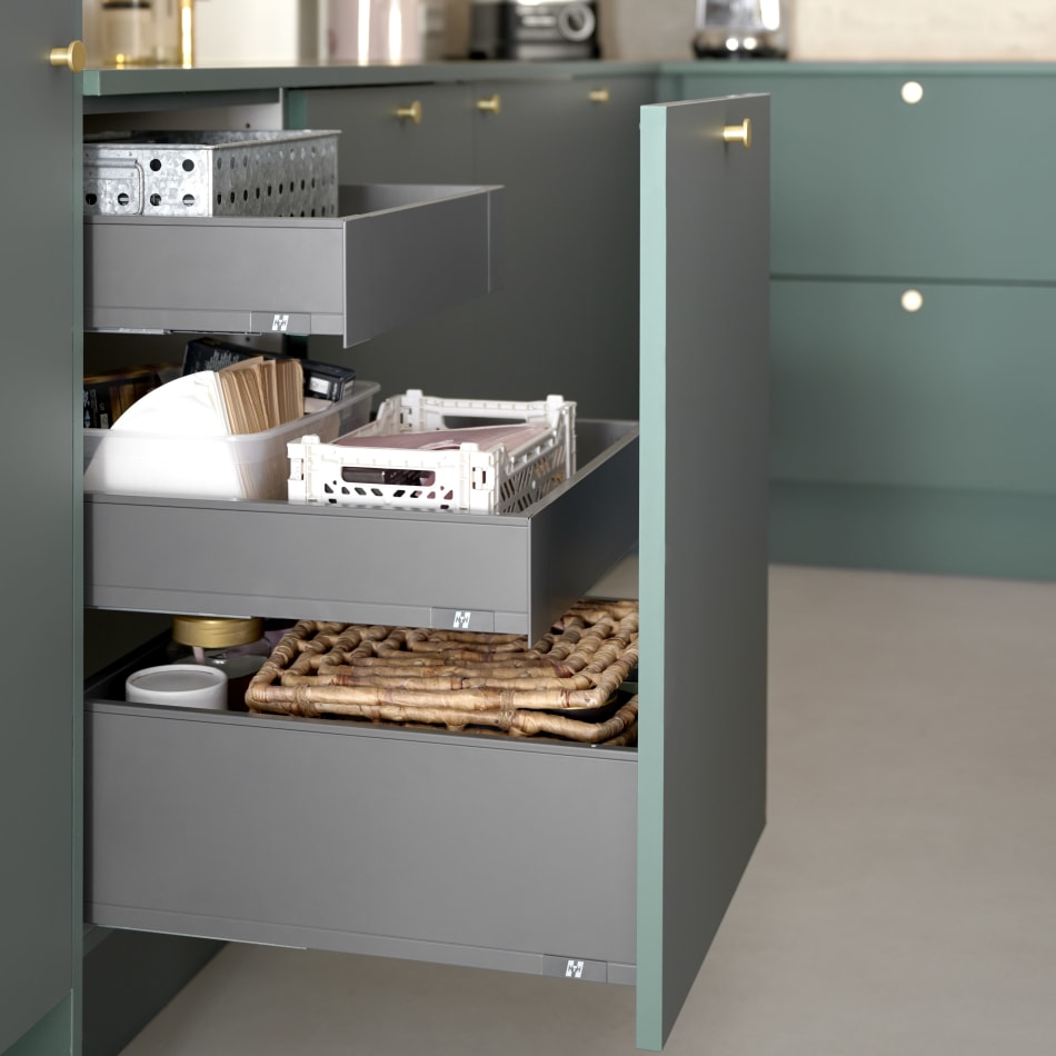 Green kitchen cabinets with open drawers displaying storage solutions | HTH