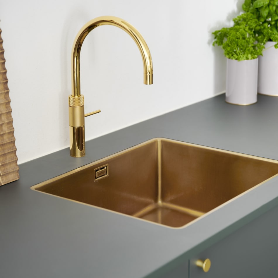 Gold sink and faucet on gray countertop. Green cabinets visible | HTH