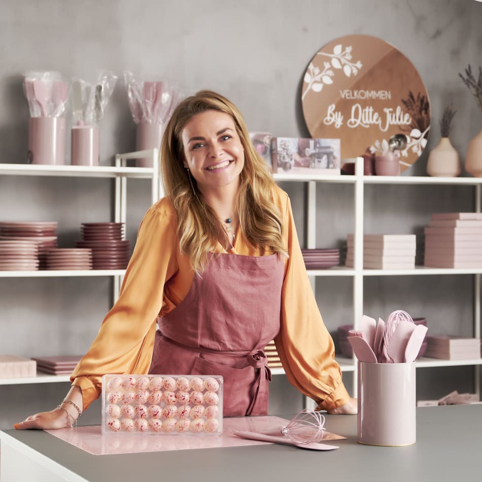 Person in pink apron in front of pink kitchenware display | HTH
