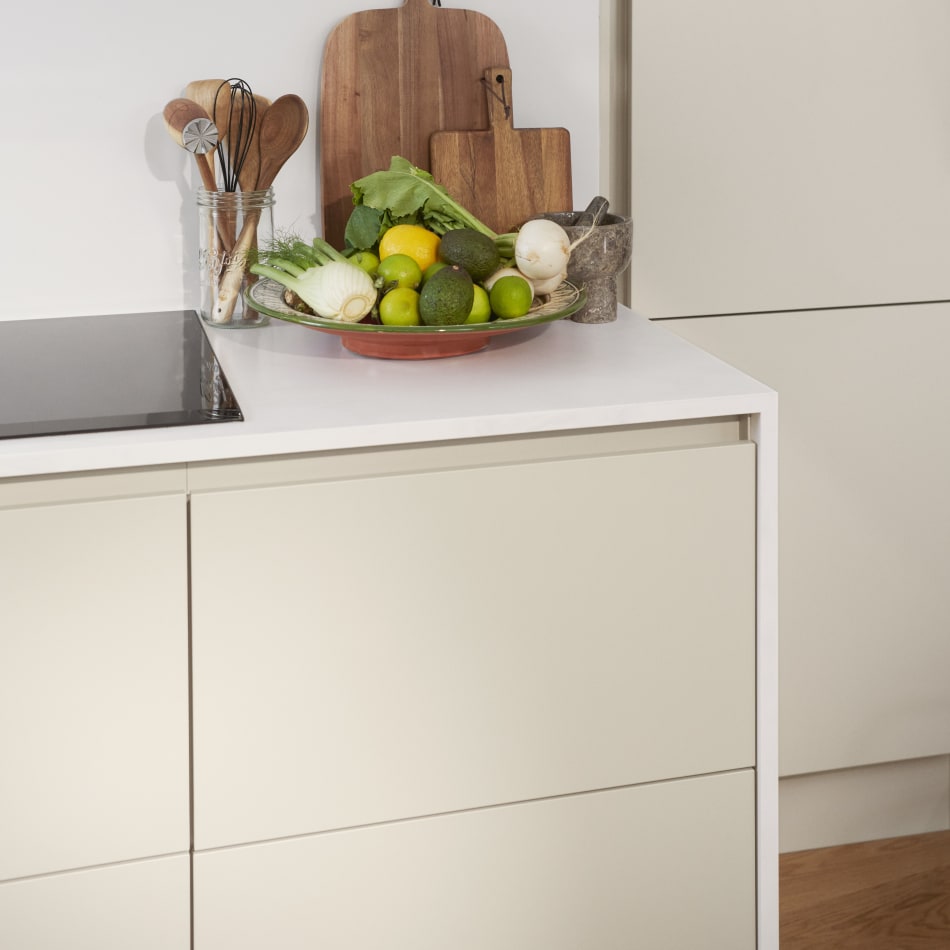 Beige kitchen cabinets with white countertop, wooden cutting boards visible | HTH