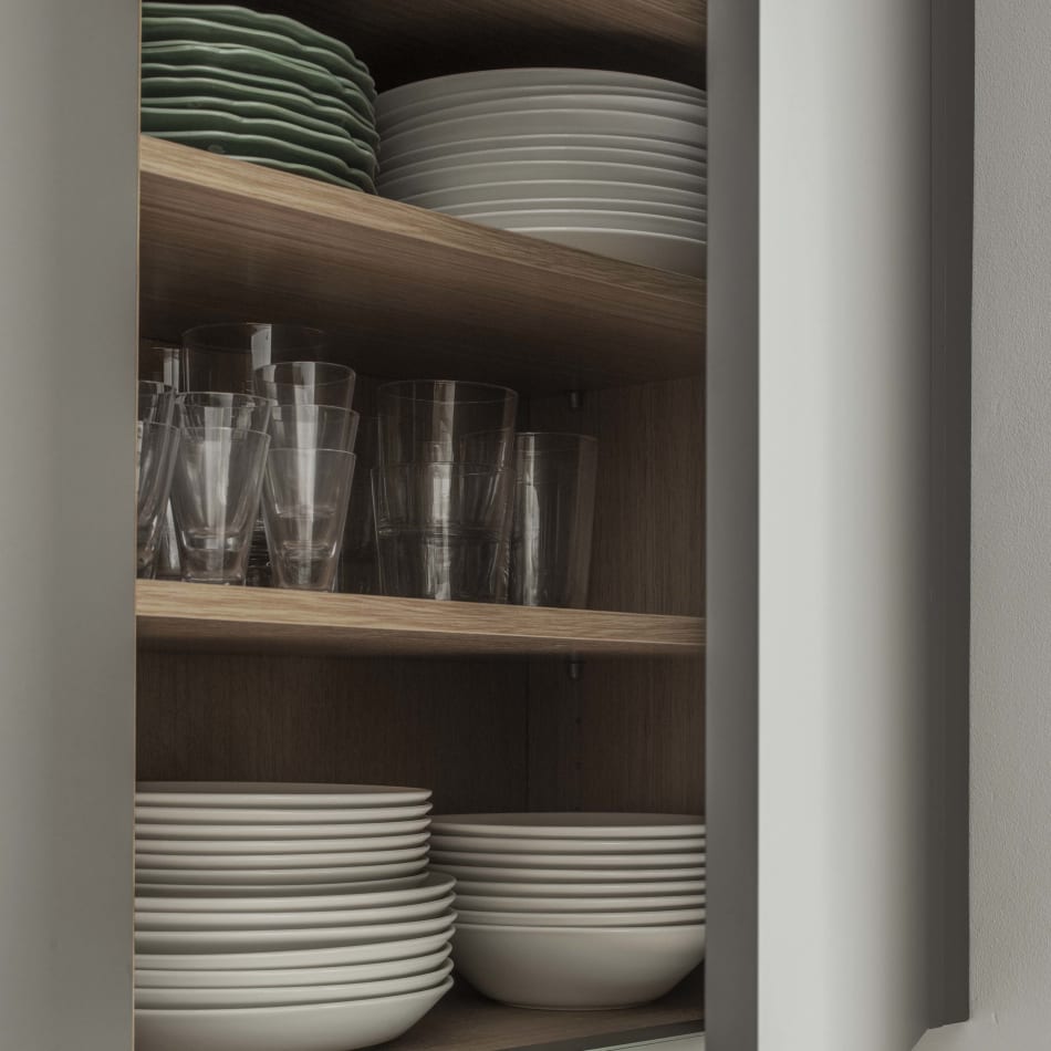 Open kitchen cabinet with wooden shelves and stacked white plates and green bowls | HTH