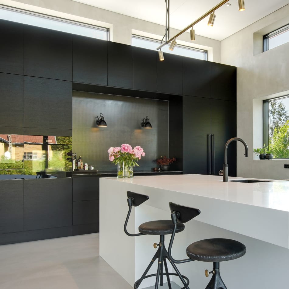 Black kitchen cabinets with white kitchen island and two black stools | HTH