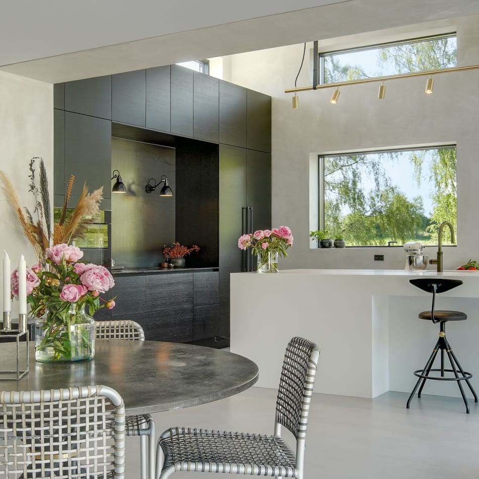 Black kitchen cabinets and white kitchen island with barstools in a bright room | HTH