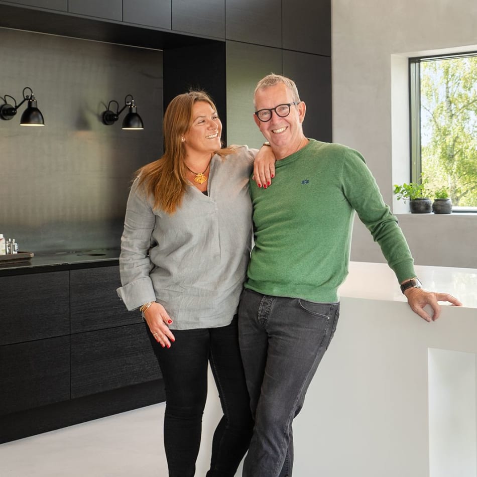 Two persons in a kitchen with black cabinets and a white kitchen island | HTH