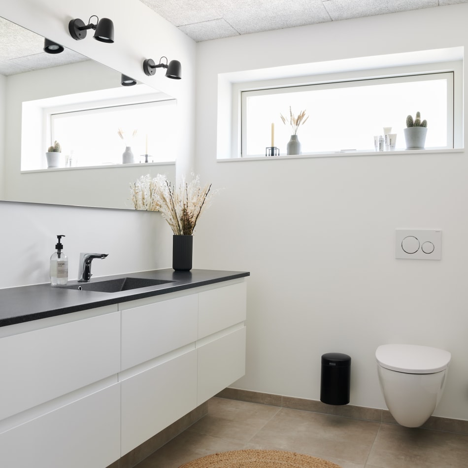 White bathroom cabinets with black countertop and wall-mounted sink | HTH