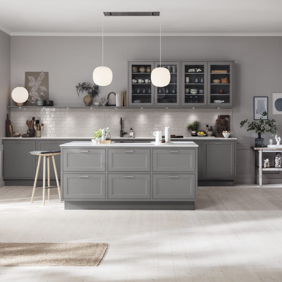 Gray kitchen with kitchen island, white countertop, and pendant lights. Model Art | HTH