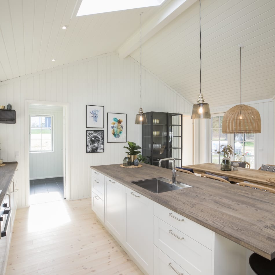 White kitchen with wood countertops and black cabinet accents. Model Art | HTH