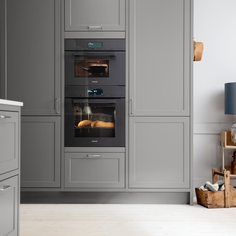 Gray kitchen cabinets with built-in oven and white countertop. Model Art | HTH