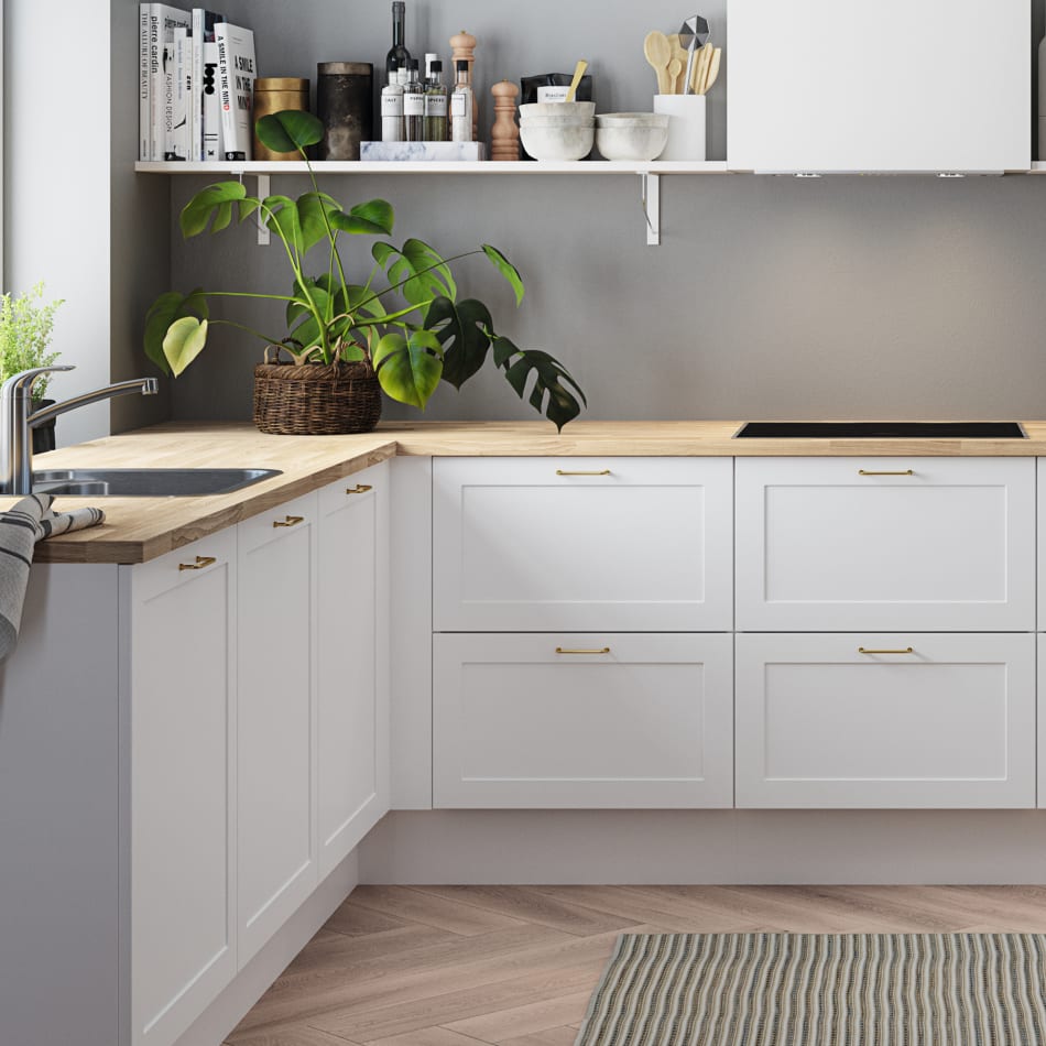 White kitchen cabinets with light wood countertop and silver faucet. Model Art | HTH