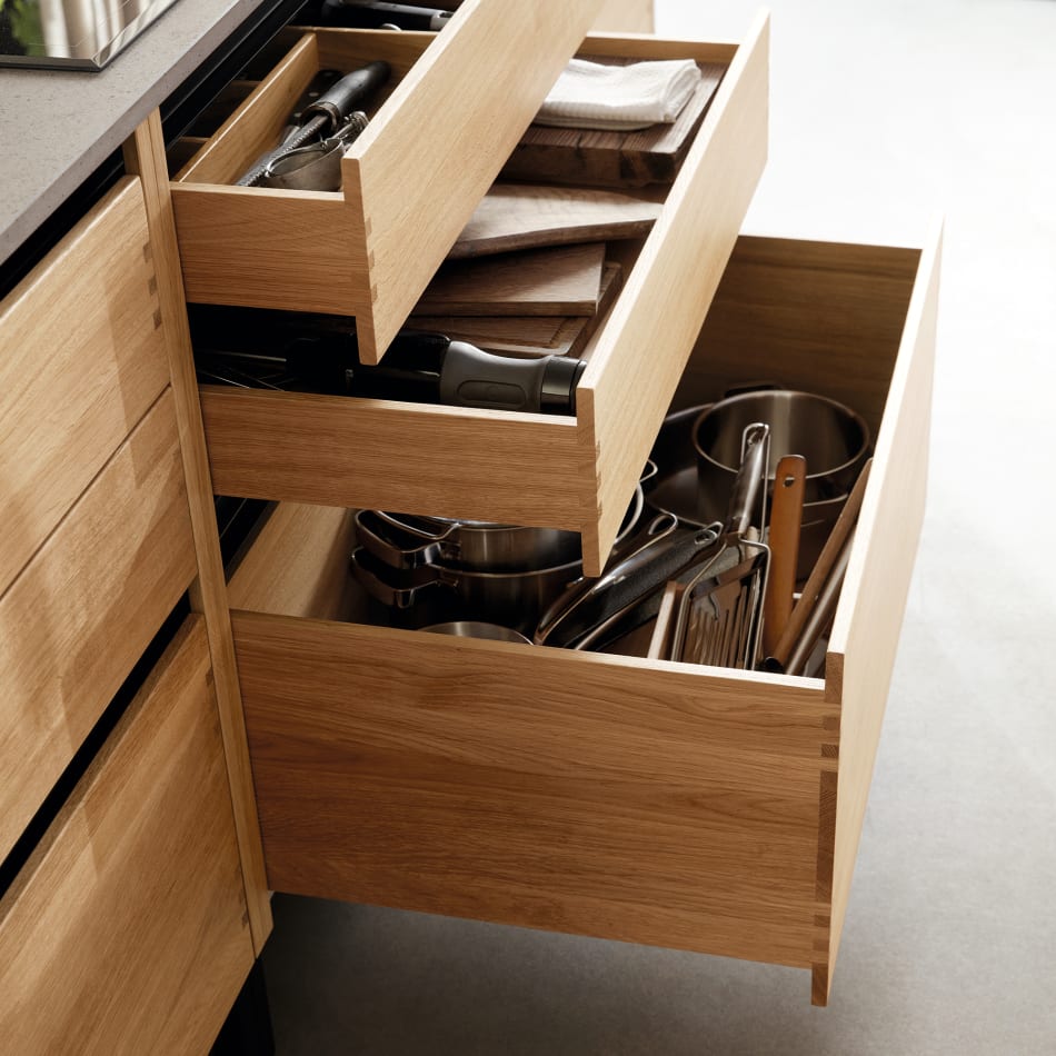 Wooden kitchen drawers with utensils, black countertop above. Nordic Creation | HTH