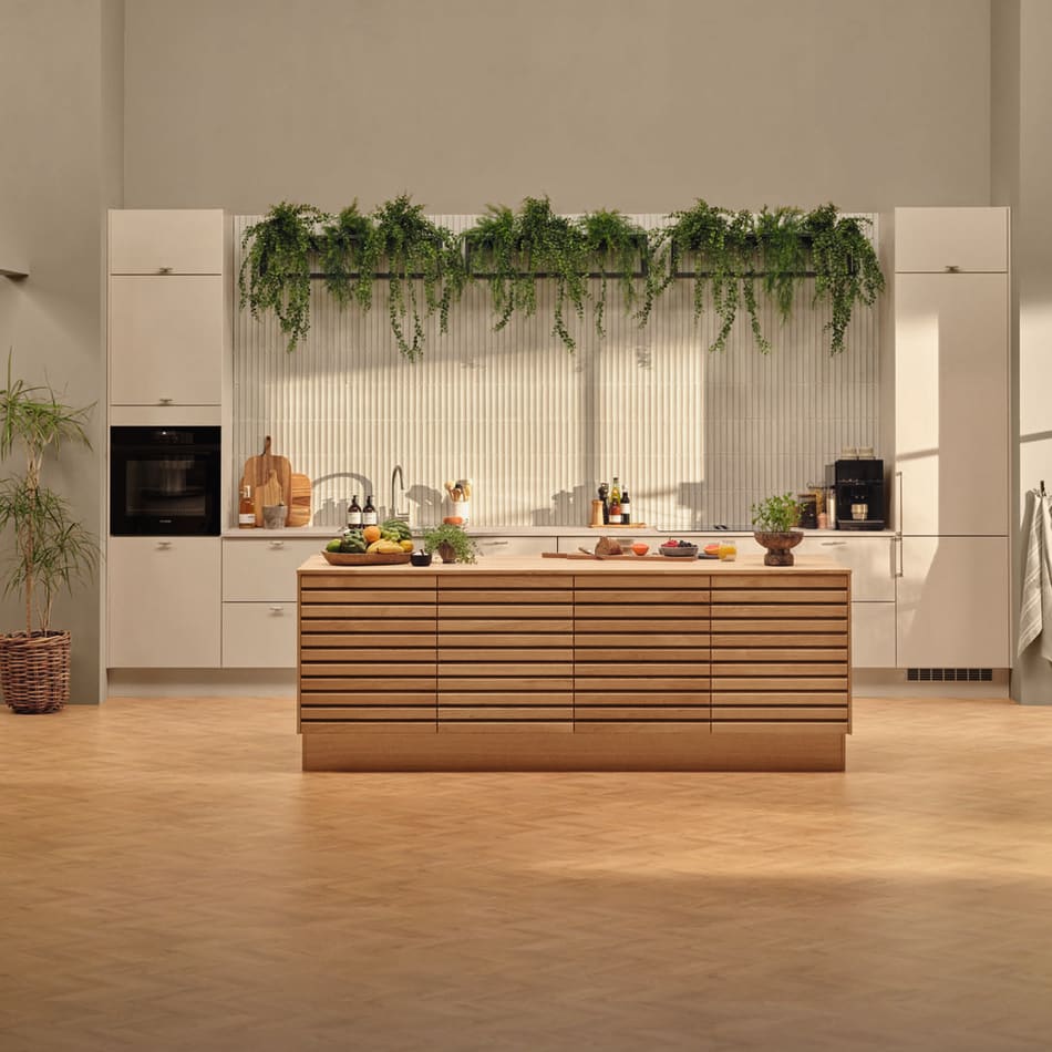 Beige kitchen with wooden island, black oven, and green plants above cabinets. Reflection | HTH