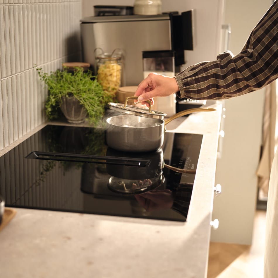 Beige kitchen with black cooktop and light gray countertop. Reflection | HTH
