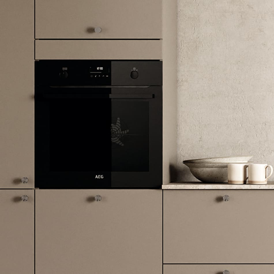 Beige kitchen cabinets with black oven and light countertop. Stockholm Kitchen | HTH