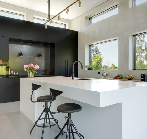 Black kitchen cabinets and white kitchen island with two stools in bright kitchen | HTH
