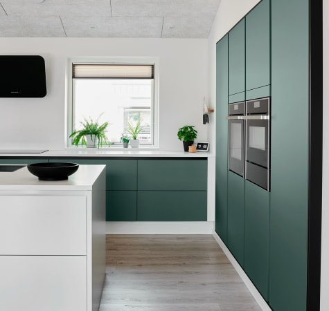 Green kitchen cabinets and white kitchen island with wood floor | HTH