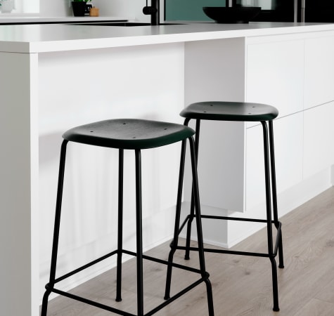 White kitchen island with black stools and green cabinets | HTH