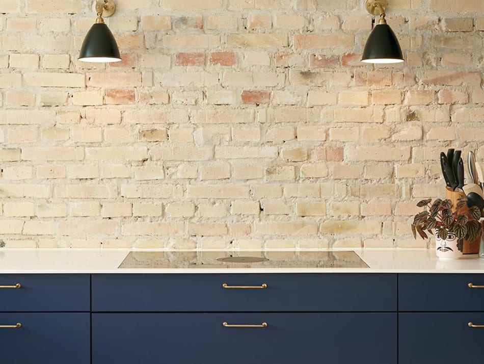 Blue kitchen cabinets with white countertop against brick wall | HTH