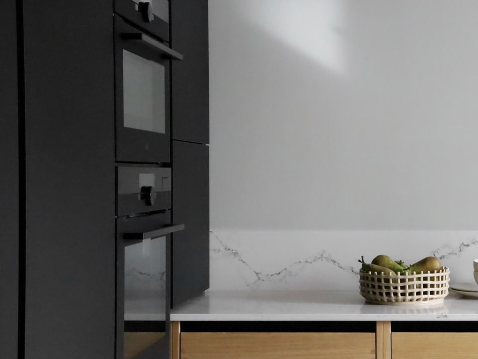 Black cabinets and light wood drawers in kitchen. White countertop visible | HTH