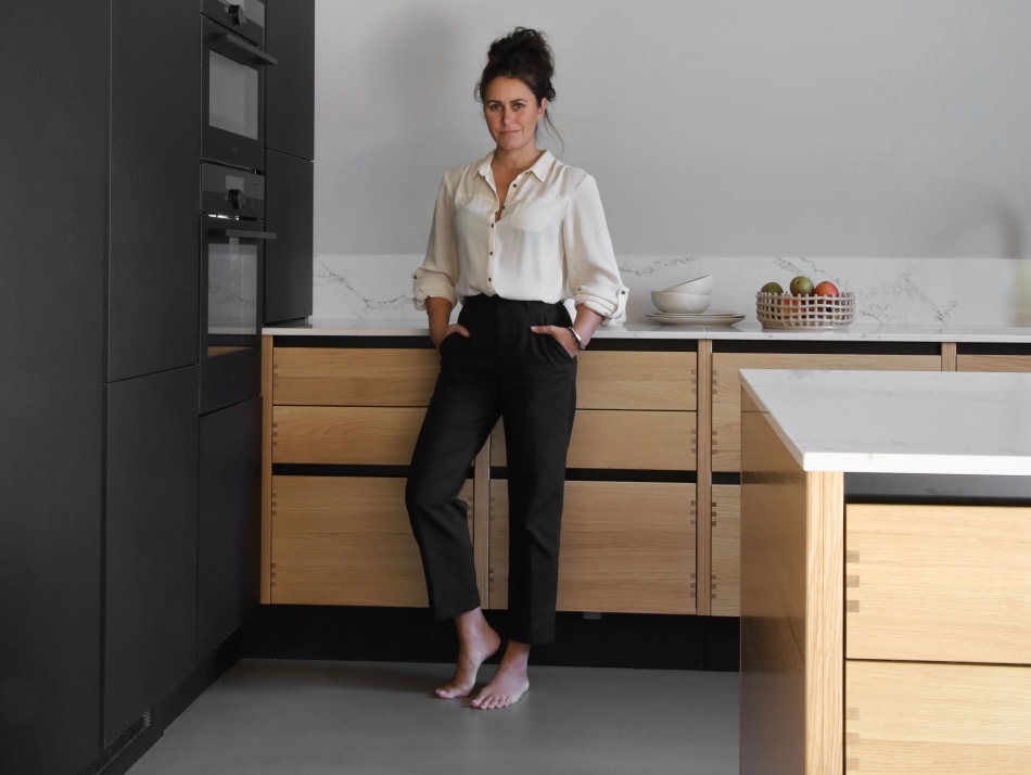 Person in kitchen with black cabinets and wood drawers, white countertop | HTH