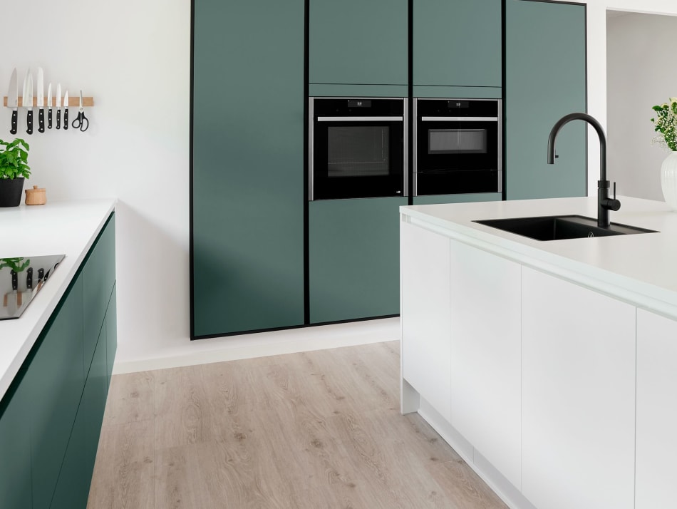 Green kitchen cabinets with white kitchen island and black faucet | HTH