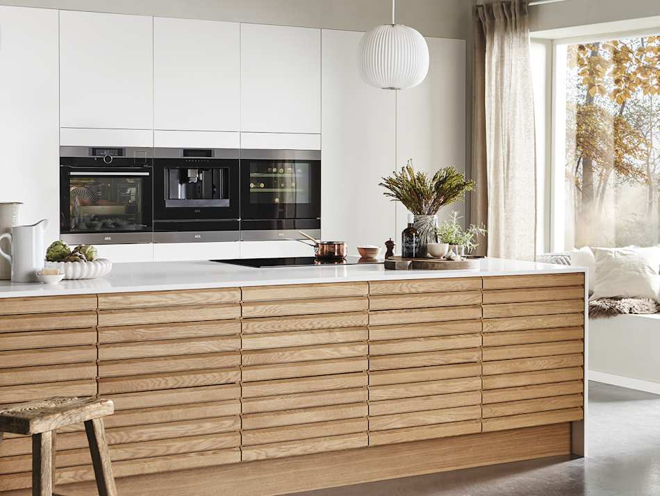 Wooden kitchen cabinets with white countertop and built-in appliances. Nordic Spirit | HTH