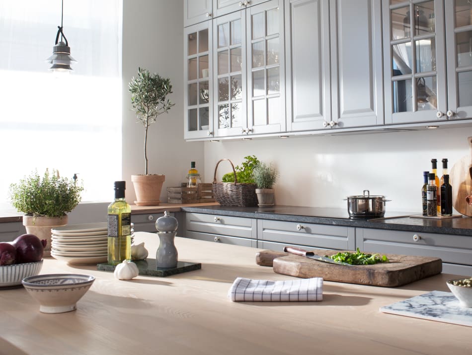 Gray kitchen cabinets with glass doors and a light wood countertop. Scandinavian Classic | HTH
