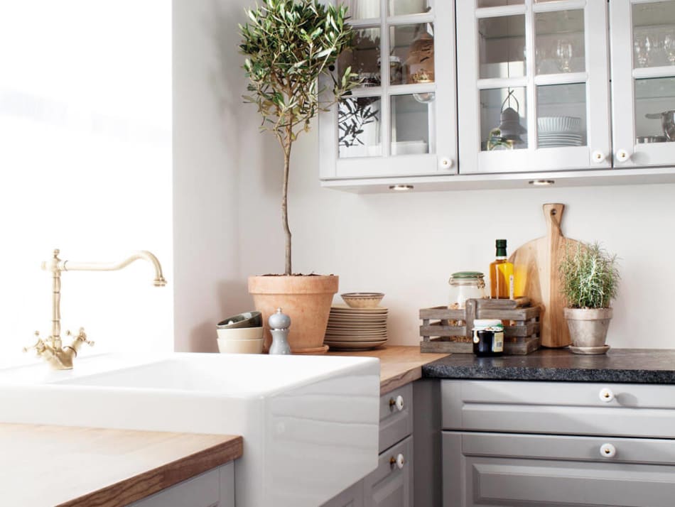 Gray kitchen cabinets with glass doors, white farmhouse sink, and wood countertop. Scandinavian Classic | HTH