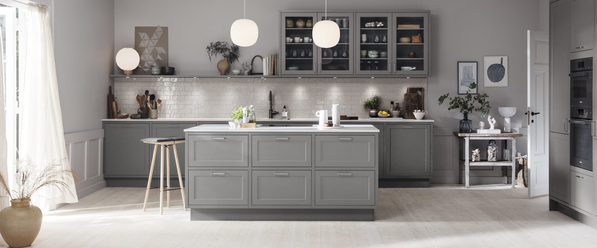 Gray kitchen with kitchen island, white countertop, and hanging pendant lights. Model Art | HTH