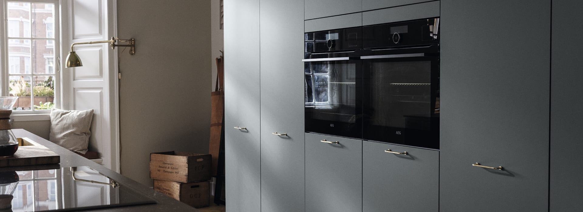 Green kitchen cabinets with built-in oven and dark countertop. Model Base | HTH