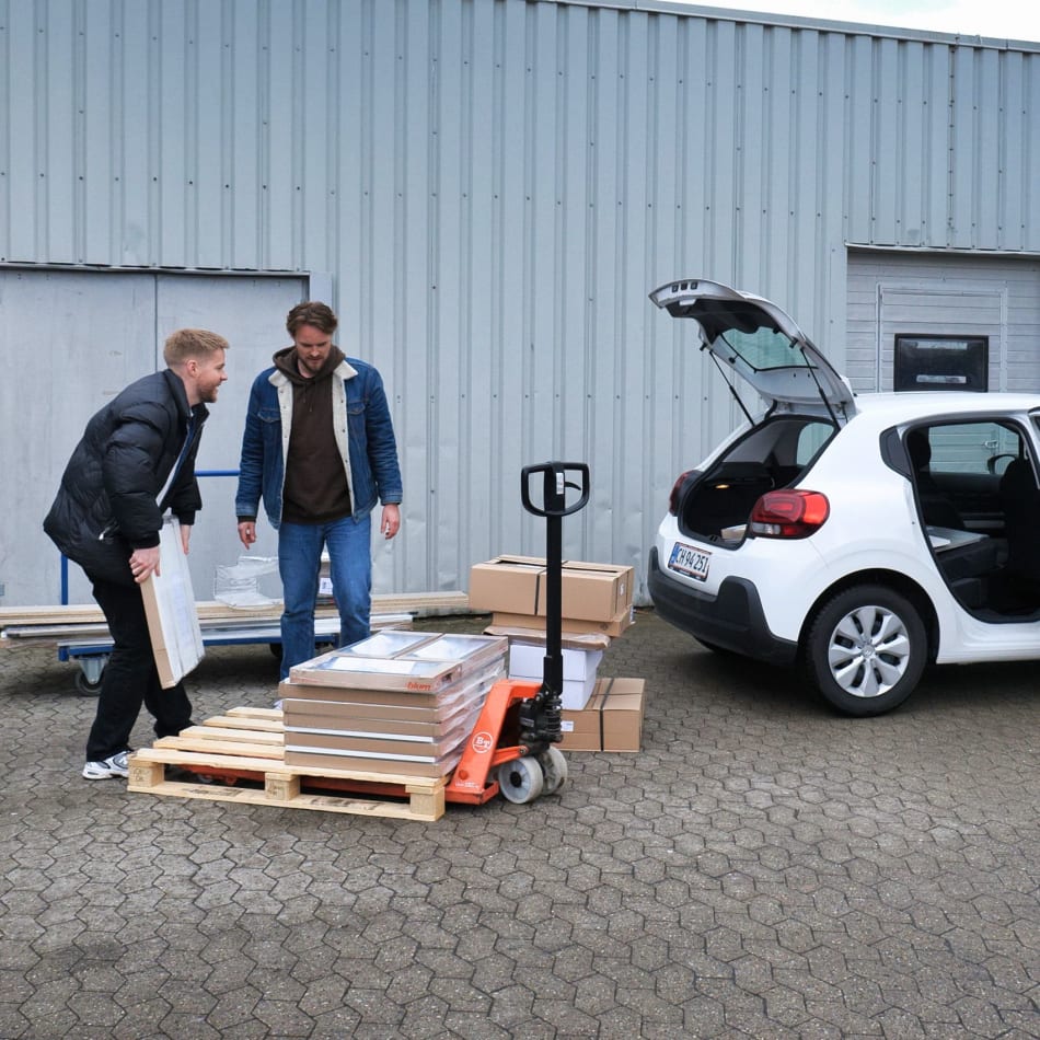Personer læsser HTH køkkenprodukter ind i en hvid bil | HTH