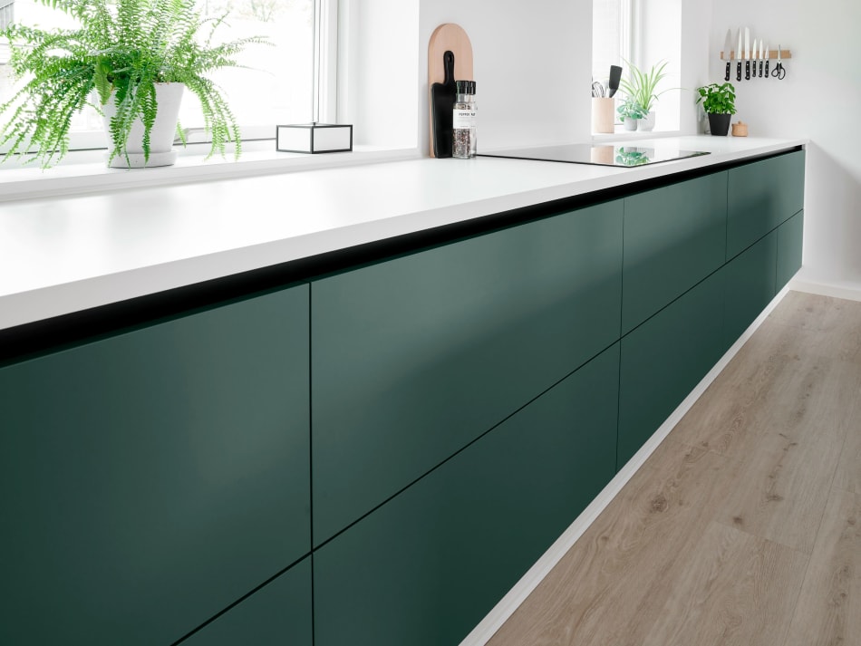 Green cabinetry paired with a white countertop, complemented by a wooden floor | HTH