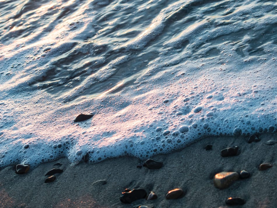 a close up of a wave crashing on a sandy beach