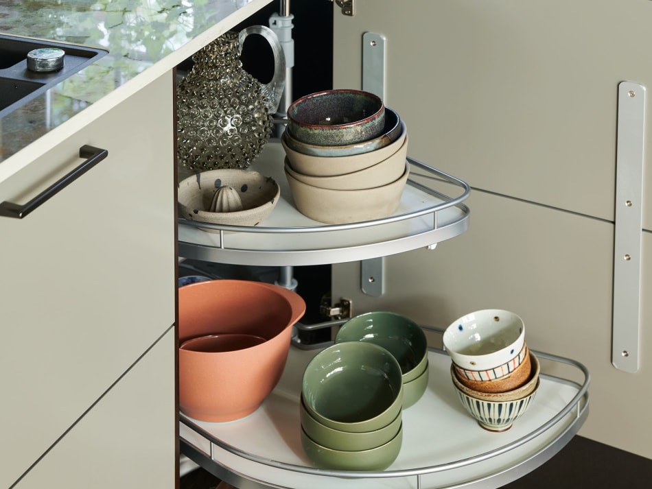 Corner cabinet with rotating shelves holding bowls in various colors | HTH